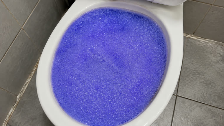 A toilet bowl completely covered rim to rim in thick violet foam